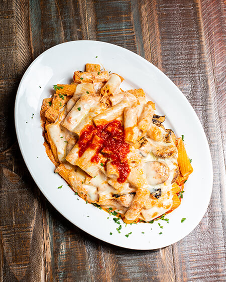 Baked Rigatoni plated on a round white dish and placed on a wooden table