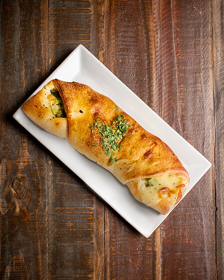 A beautifully presented Broccoli Roll on a wooden counter — $7.50