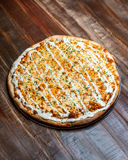 A beautifully presented Buffalo Chicken pizza pie on a wooden counter — $19.25