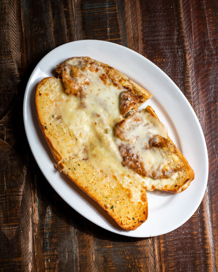 A beautifully presented Chicken Francese on Garlic Bread with Mozzarella Hot Sandwich on a wooden counter — $9.95