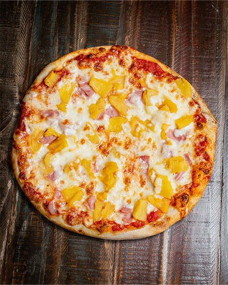 A beautifully presented Hawaiian pizza pie on a wooden counter — $17.60