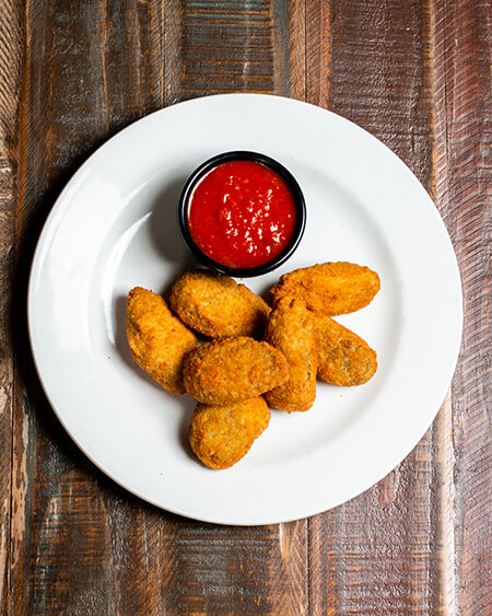 A beautifully presented plate of Jalapeño Cheese Poppers with marinara sauce on a wooden counter — $7.50