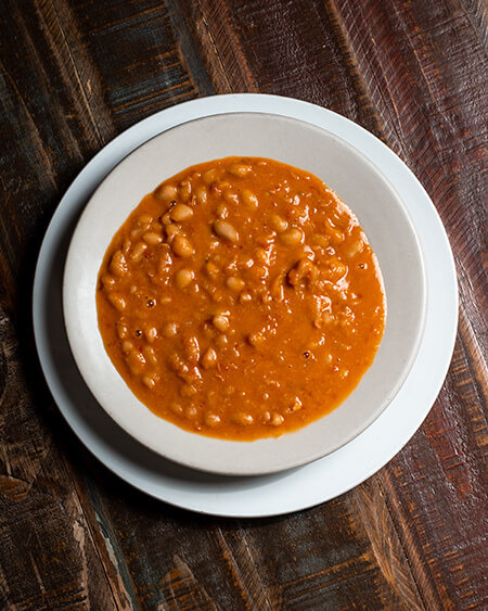 A beautifully presented plate of Pasta Fagioli on a wooden counter — $6.95
