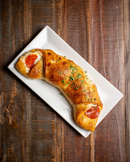 A beautifully presented Pepperoni Roll on a wooden counter — $7.50