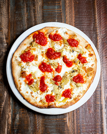 Gourmet ai carciofi pizza has Sautéed artichoke hearts, plum tomato sauce, and fresh mozzarella cheese