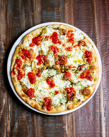 Gourmet selvatica pizza has Fresh tomato, fresh mozzarella cheese, and pesto sauce