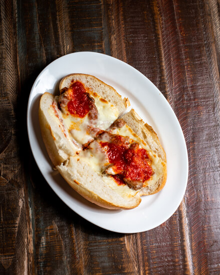 A beautifully presented Shrimp Parmigiana Hot Sandwich on a wooden counter