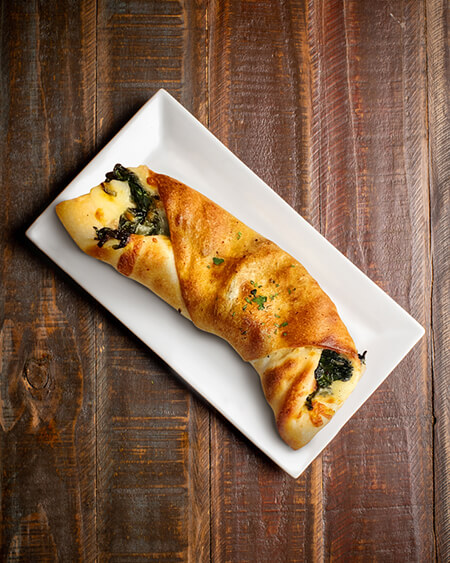 A beautifully presented Spinach Roll on a wooden counter — $7.50