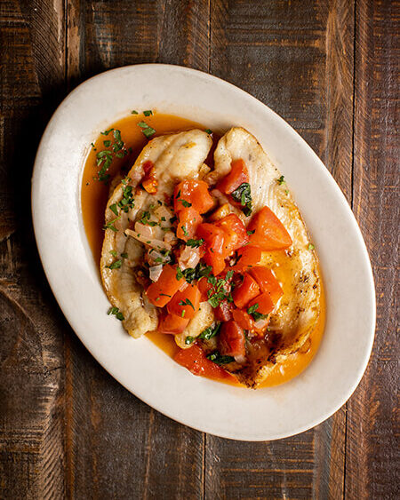 A beautifully presented plate of Flounder Marechiare on a wooden counter — $18.95