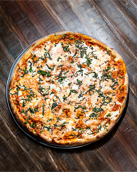 A beautifully presented Vodka & Fresh Mozzarella pizza pie on a wooden counter — $20.35
